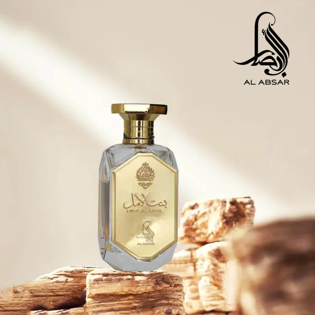 Perfume bottle with gold and clear design on a wooden background, featuring the Al Absar brand logo.