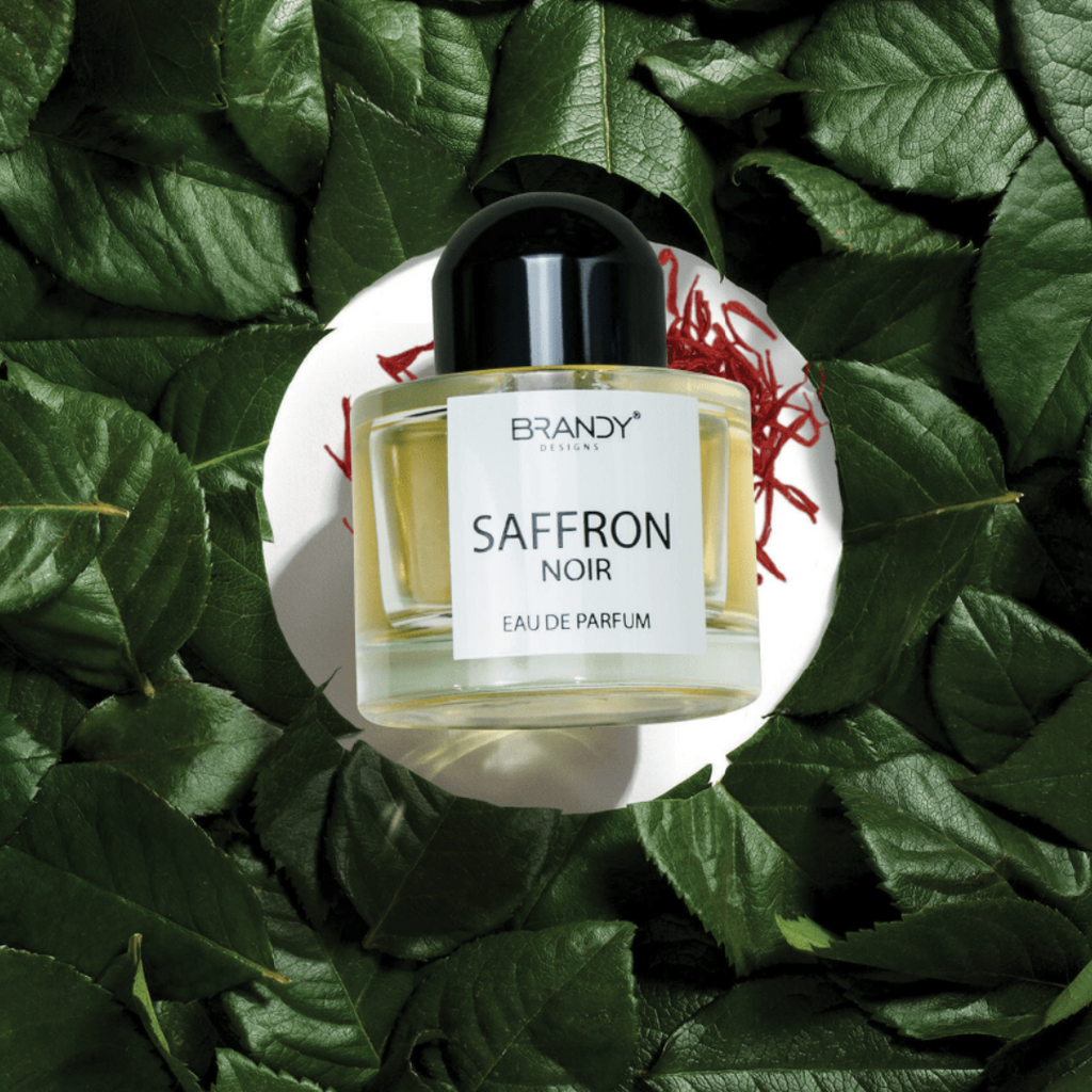 Perfume bottle labeled 'Saffron Noir' by Brandy on a leafy background
