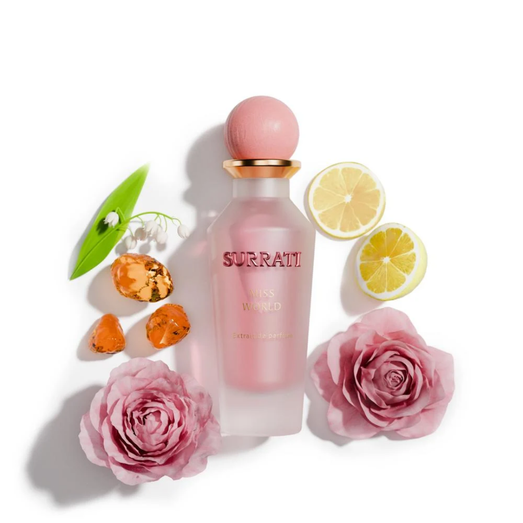 Pink Surrati perfume bottle with flowers and citrus slices on a white background